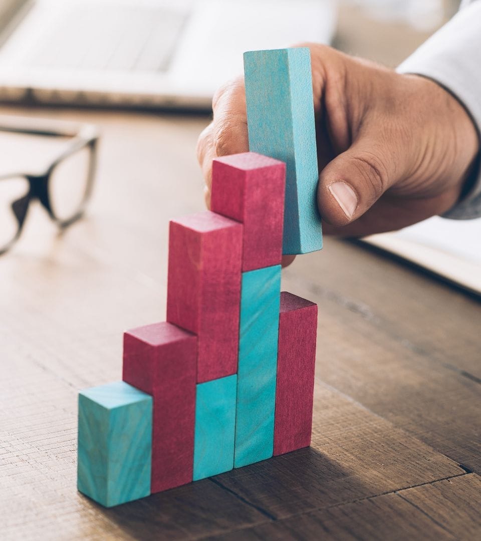 person building a little wooden brick staircase that stand for a increase in sales