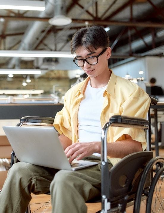 person sitting in wheelchair working on a laptop