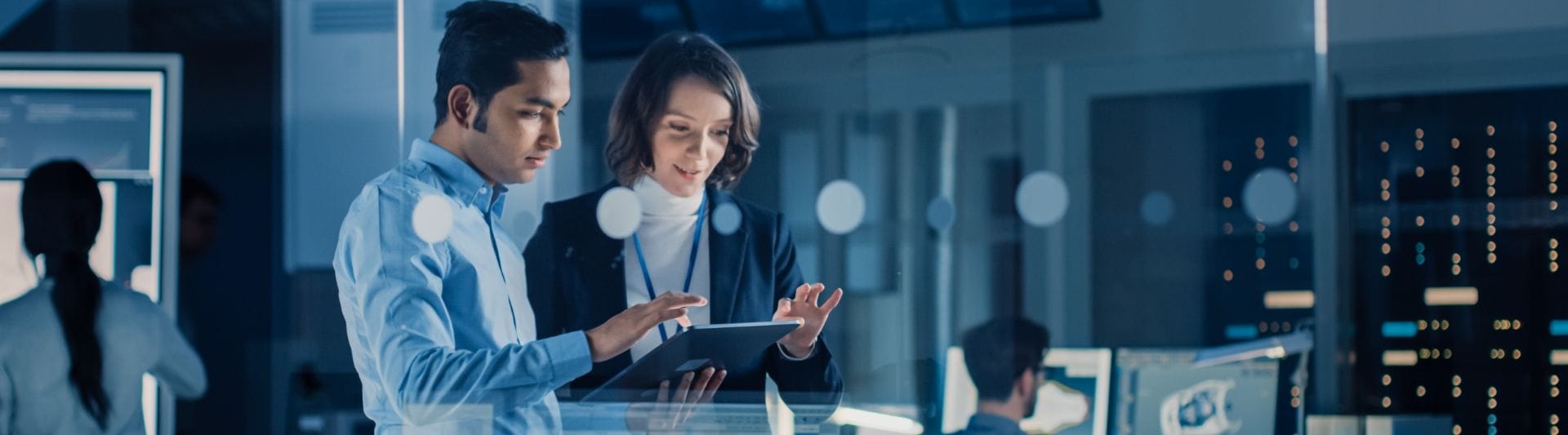 2 people standing next to each other looking a a tablet