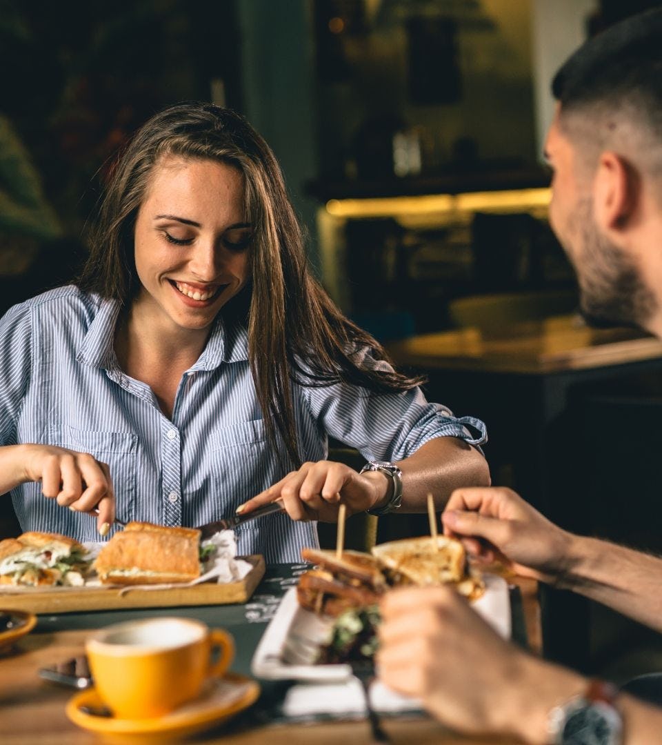 one woman and one man eating togheter on a date inside a restaurant