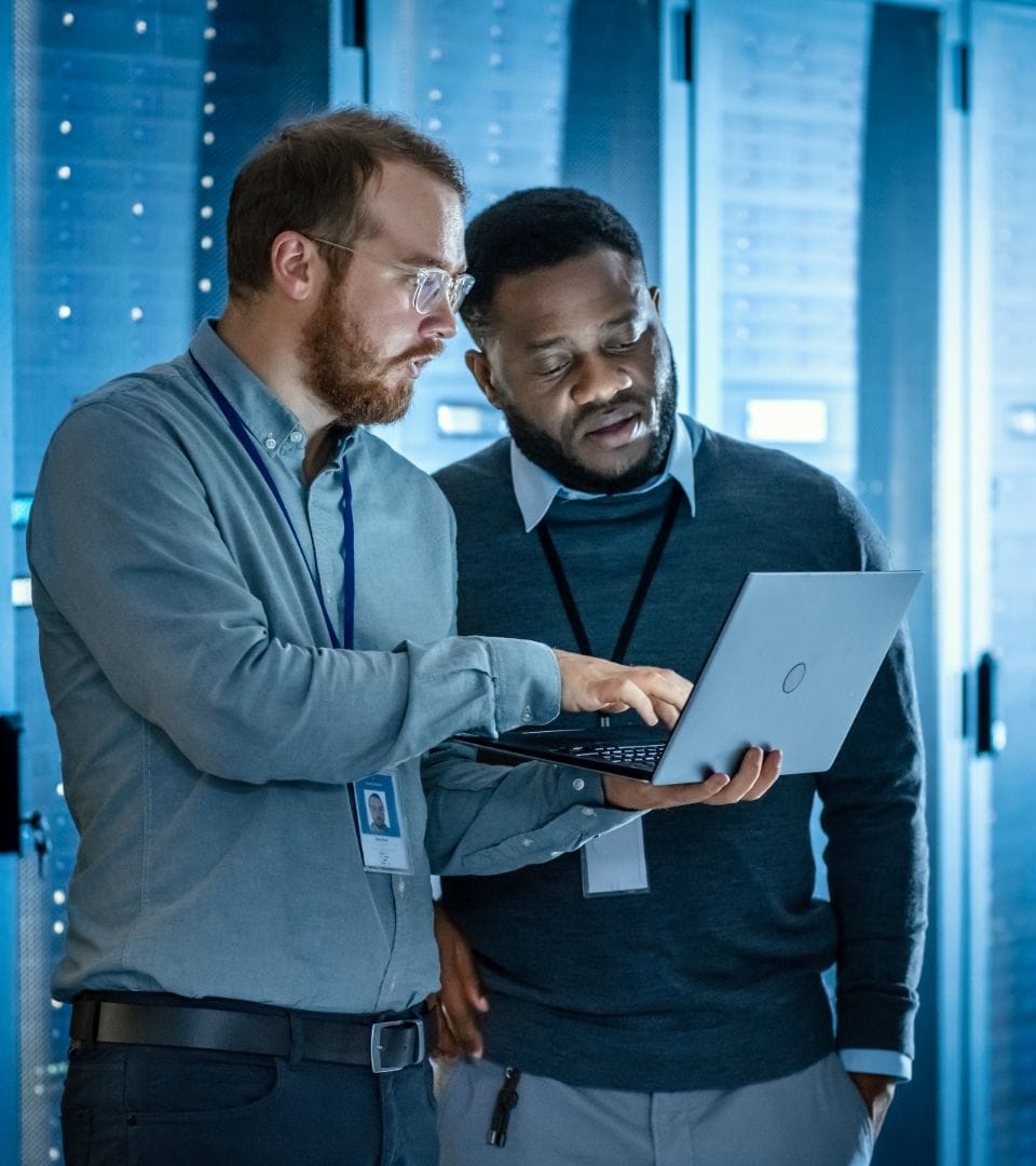 A male showing another male something on a laptop