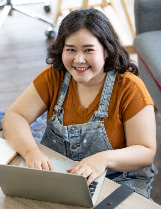 A laughing girl sitting in front of a laptop working